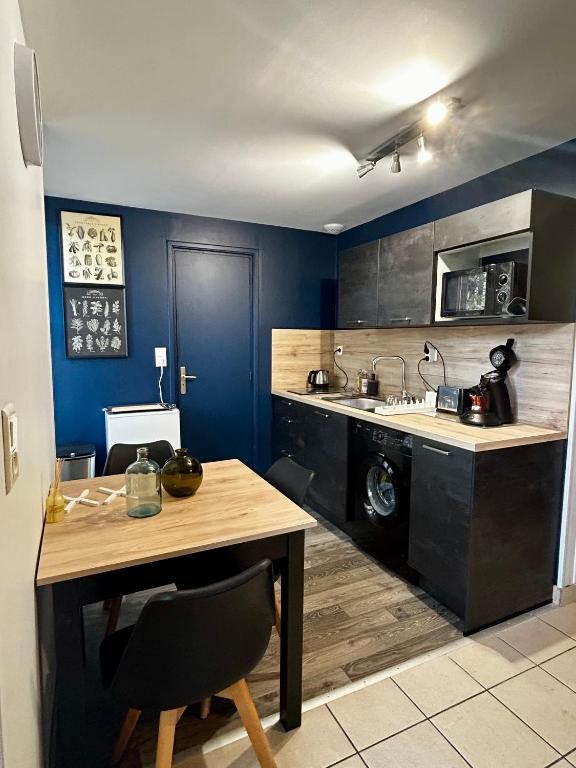 a kitchen with blue walls and a table and a stove at Centre ville - Berthelot in Chamalières