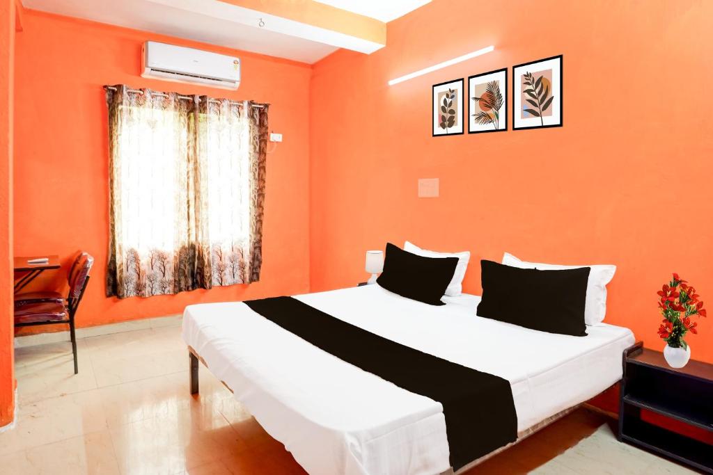 a bedroom with a large bed with an orange wall at HOTEL O PRAGYA 6 in Raipur