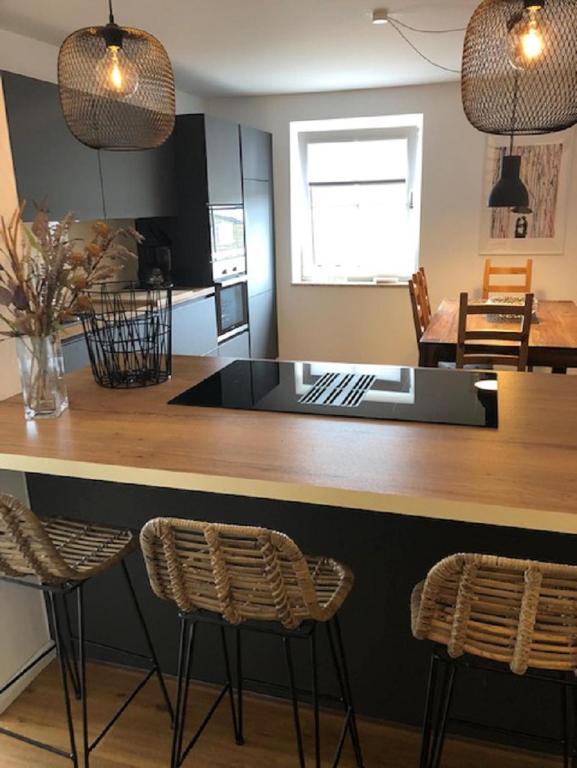 a kitchen with a counter and two stools at Welcome in Petersdorf auf Fehmarn
