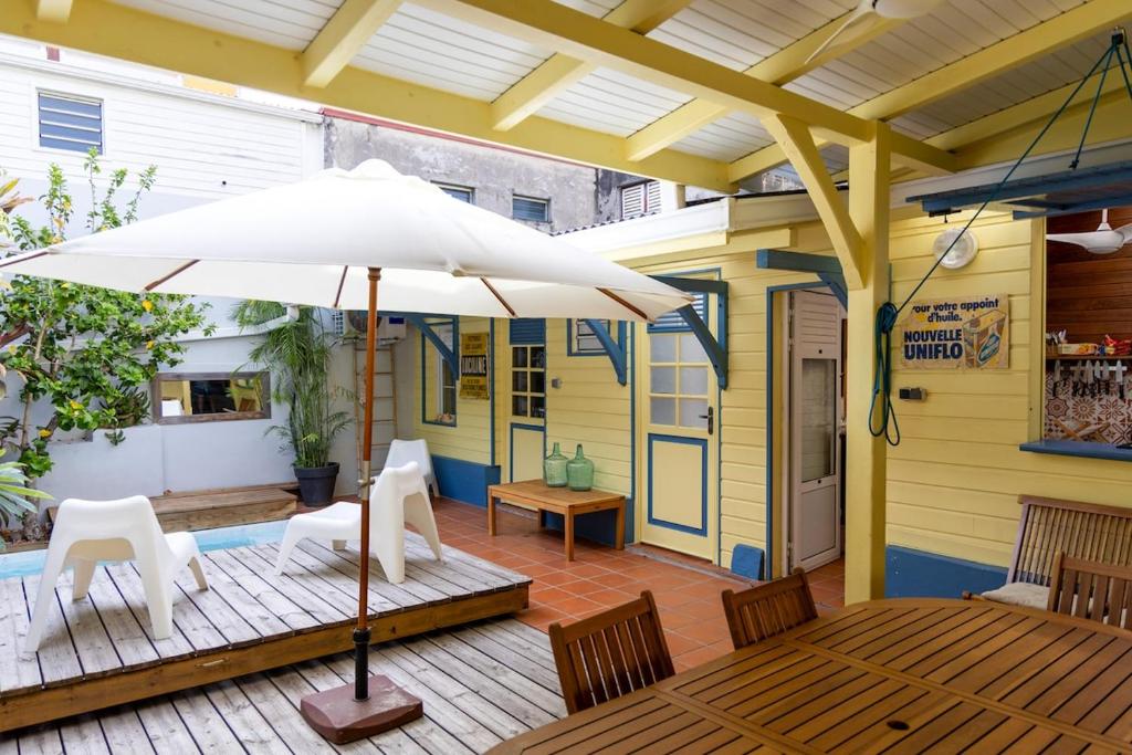 a patio with a table and an umbrella at La Maison Jaune - Swimming pool & beach access 50 m away in Saint-Pierre