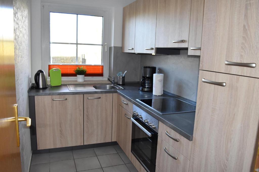 a kitchen with wooden cabinets and a sink and a stove at Unsere Wenke in Wenkendorf auf Fehmarn