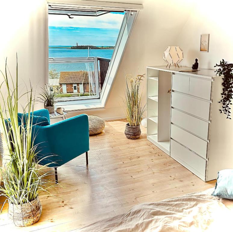 un soggiorno con una sedia blu e una grande finestra di meerBLICK a Orth