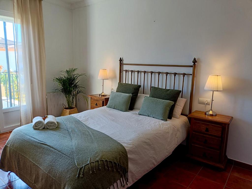 een slaapkamer met een bed met groene kussens en 2 lampen bij La Casa Del Platero in Ronda