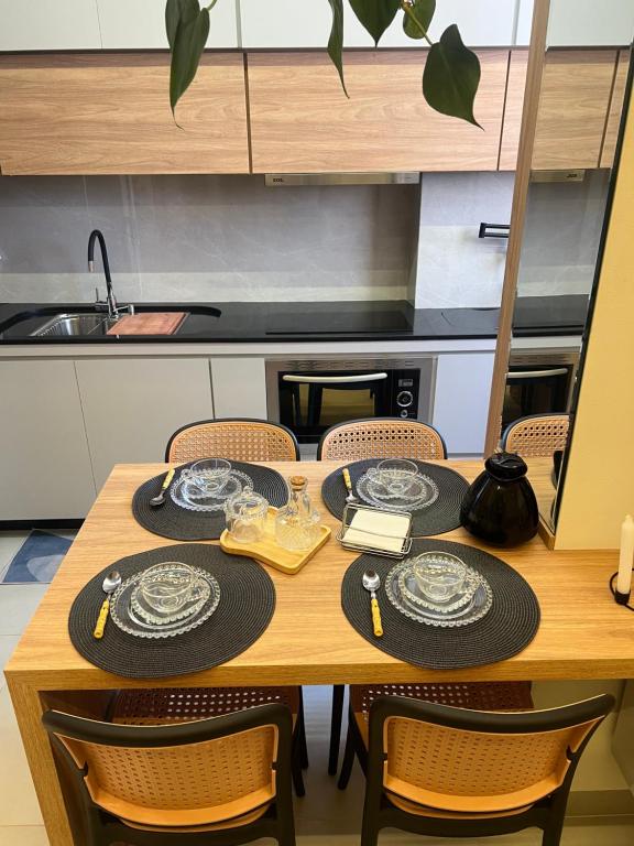 a wooden table with chairs and plates on it at Apartment Praia Clube Uberlandia in Uberlândia