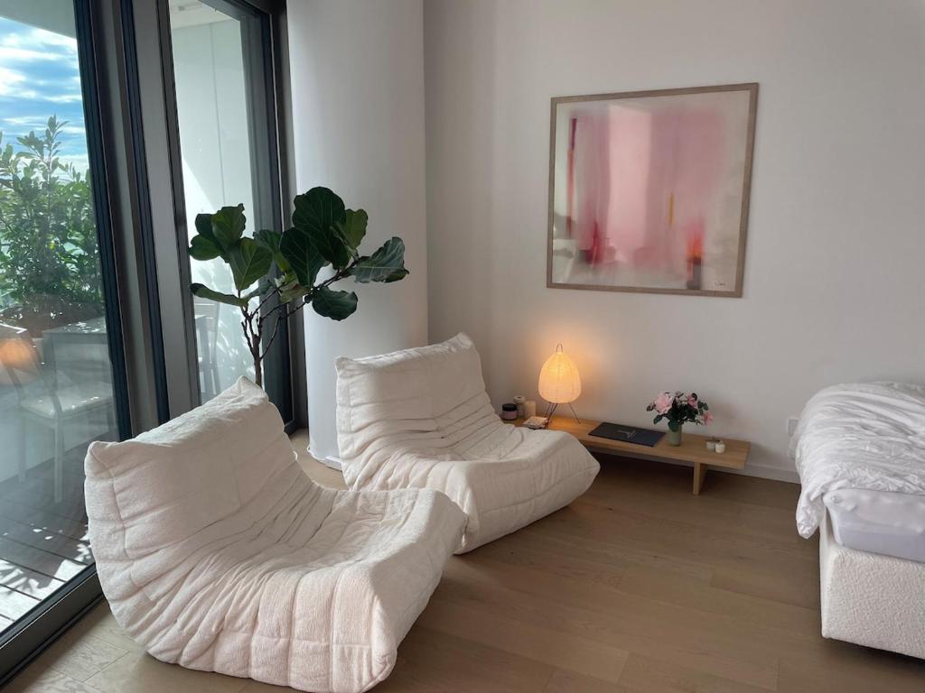 a living room with two white chairs and a table at Wellness Oase an der Donau in Wien in Vienna