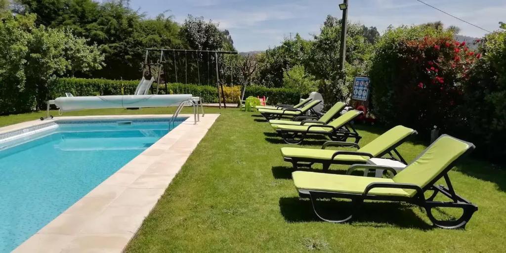 a row of lawn chairs next to a swimming pool at Paradisiacal Villa in Lousada with Private Pool in Lousada