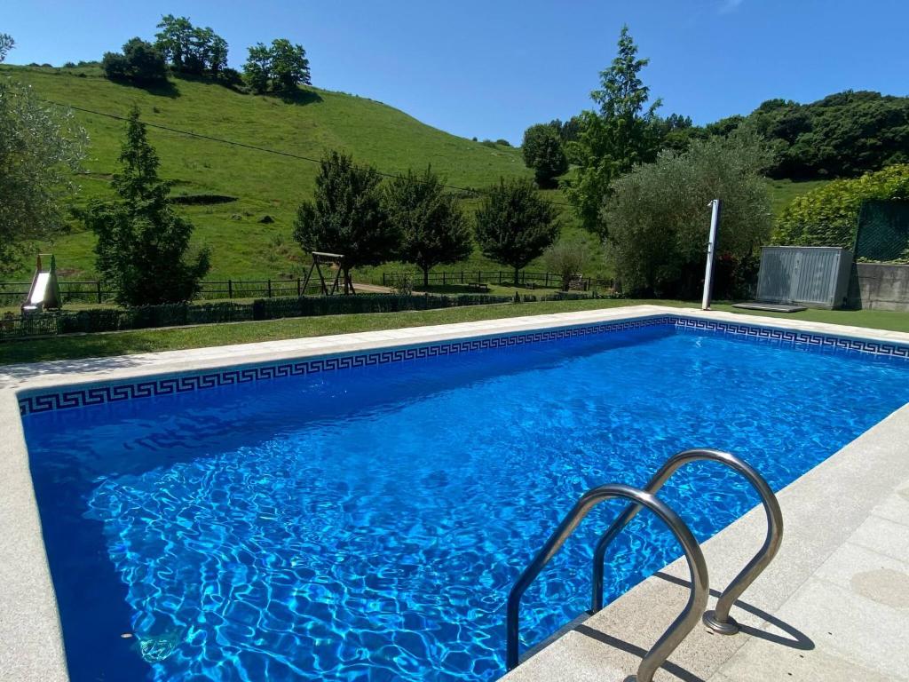 ein blauer Pool mit einem Hügel im Hintergrund in der Unterkunft Rozando el mar en puerto calderon in Oreña