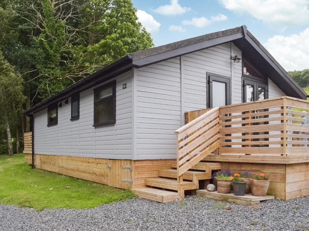 ein kleines Haus mit einer großen Terrasse in der Unterkunft Woodlands Lodge in Colmonell