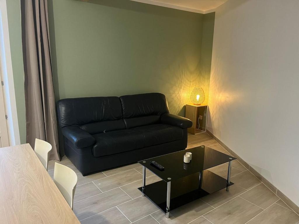 a living room with a black couch and a table at Appartement cosy rénové dans une ancienne longère in Chemilly-sur-Yonne