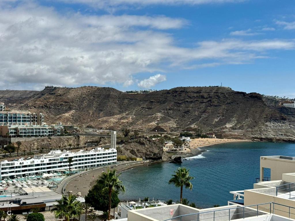 a body of water with buildings and a mountain at playa del cura apartment with terrace in Mogán