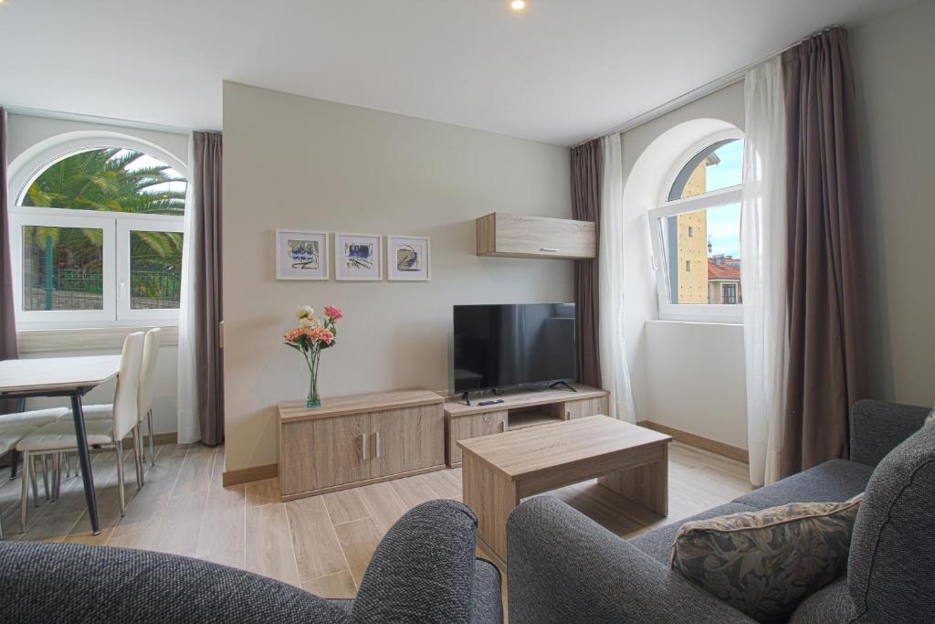 een woonkamer met een bank en een tv bij Apartamentos Turísticos La Pontificia in Comillas