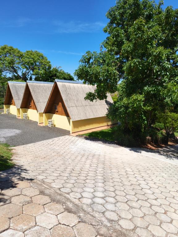 un edificio con techo de gambrel y un árbol en Chalés Magia das Águas, en Águas de Lindóia