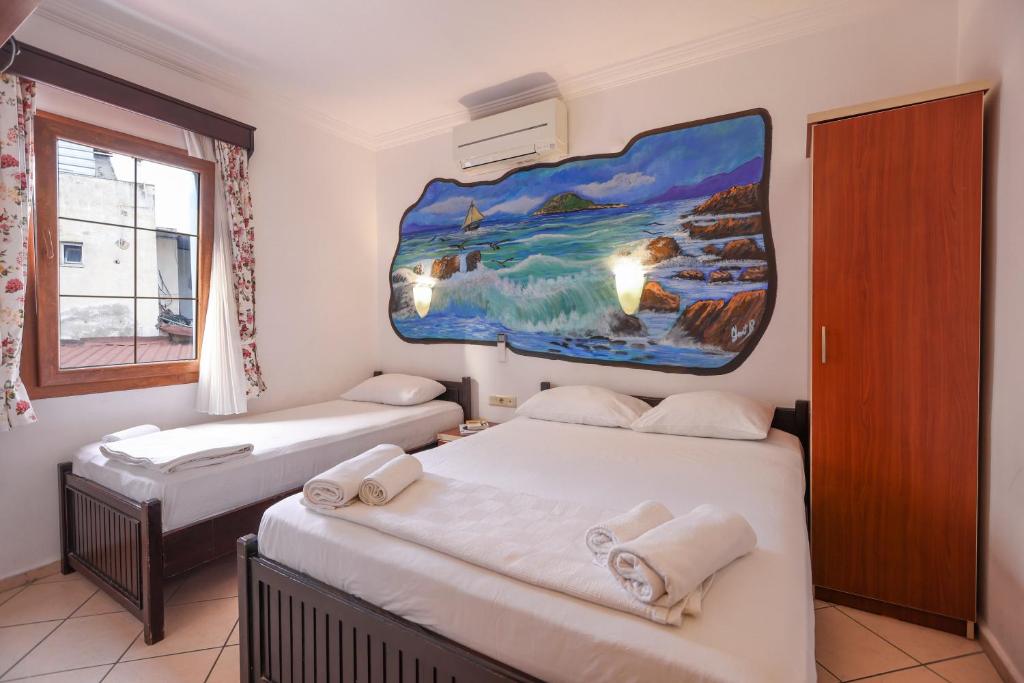 zwei Betten in einem Zimmer mit einem Gemälde an der Wand in der Unterkunft Turunç Pansiyon in Bodrum City