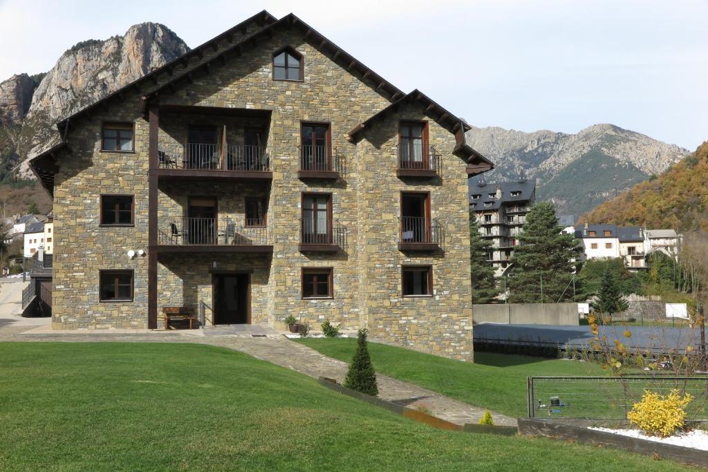 a large stone building with mountains in the background at El Molino de Pochas in Bielsa