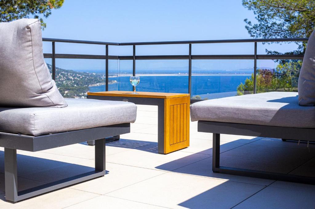 Dos sillas y una mesa en un balcón con vista. en Résidences des Peyrons vue exceptionnelle mer et sur les Iles d'Or, en Carqueiranne