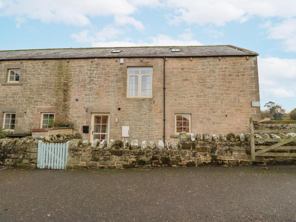 an old brick building with a fence in front of it at Watermill Cottage in Chathill