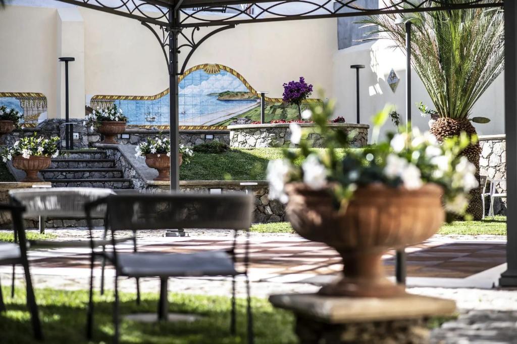 een patio met stoelen en een vaas met bloemen bij Garibaldi Houses in Milazzo