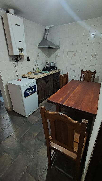 a kitchen with a wooden table and a white refrigerator at Humadepto in Humahuaca
