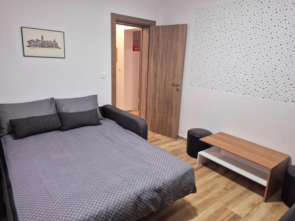 een slaapkamer met een bed, een tafel en een deur bij The Music Box in Skopje