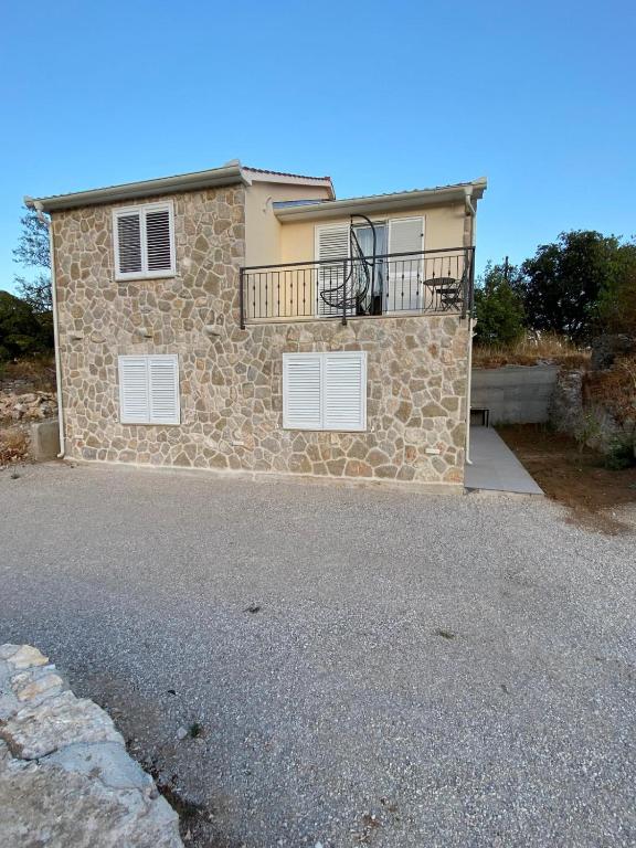 a stone house with a balcony on top of it at Apartman Lasko in Razvala