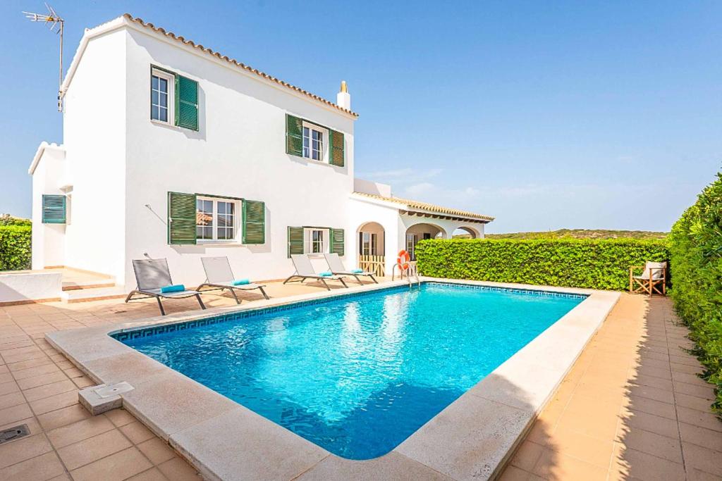 a villa with a swimming pool in front of a house at Villa Cala Llonga in Cala Llonga