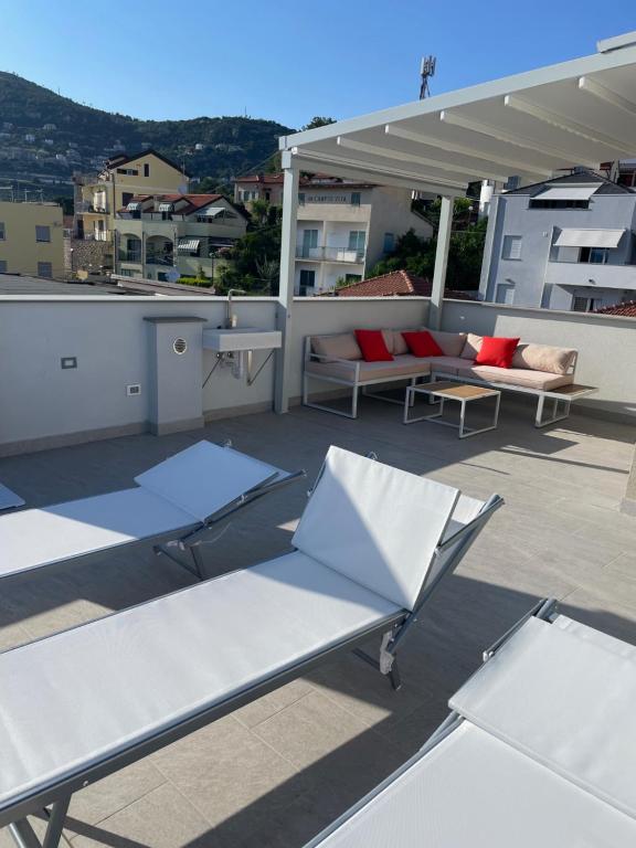 een patio met stoelen en tafels op een dak bij Appartamento Gocce di sole in Pietra Ligure