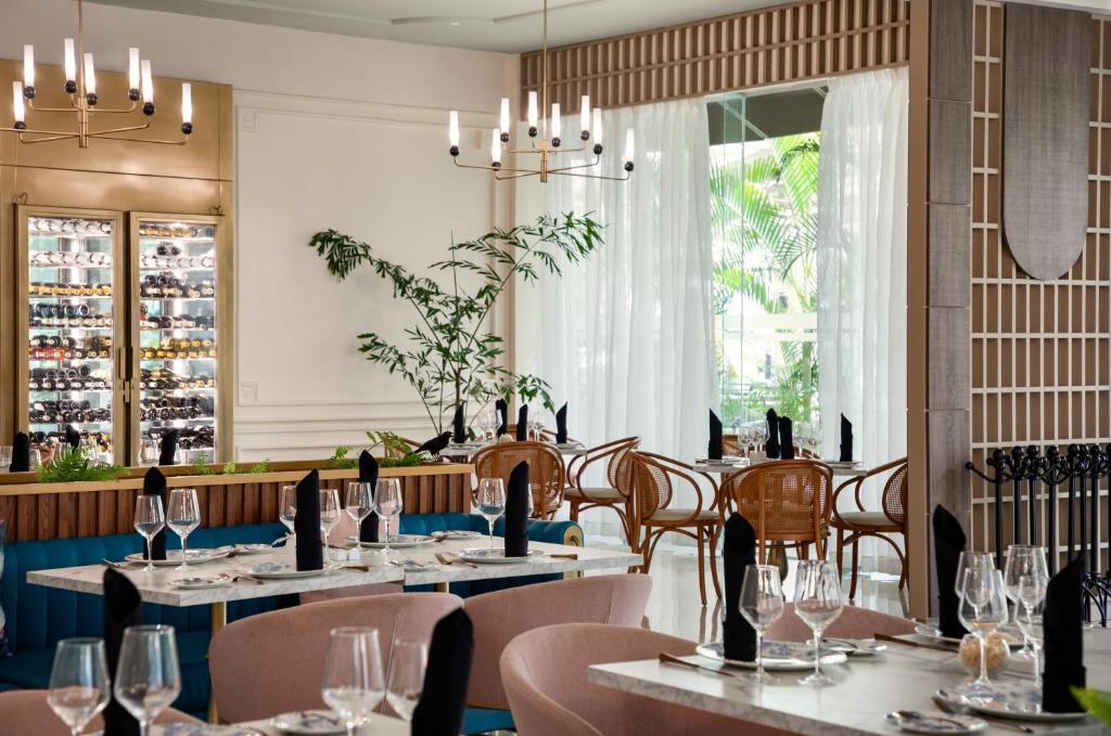 Dining room with rattan chairs, blue and pink seating, and glazed storefront windows.