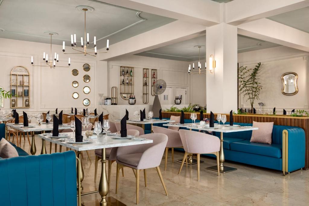 Modern dining room with blue velvet seating, marble tables, and brass lighting fixtures.