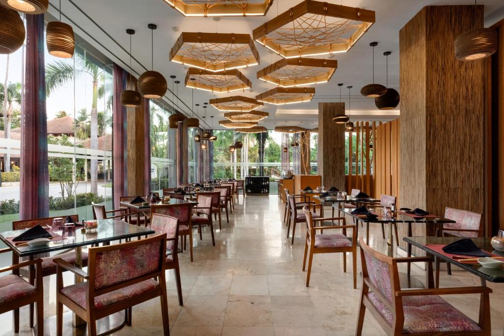 Dining room with tables set for service, wooden chairs, and large windows overlooking grounds.