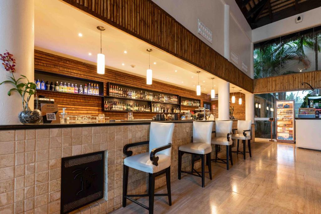 Indoor bar with wooden slat backdrop, stocked liquor shelves, and seated bar stools.