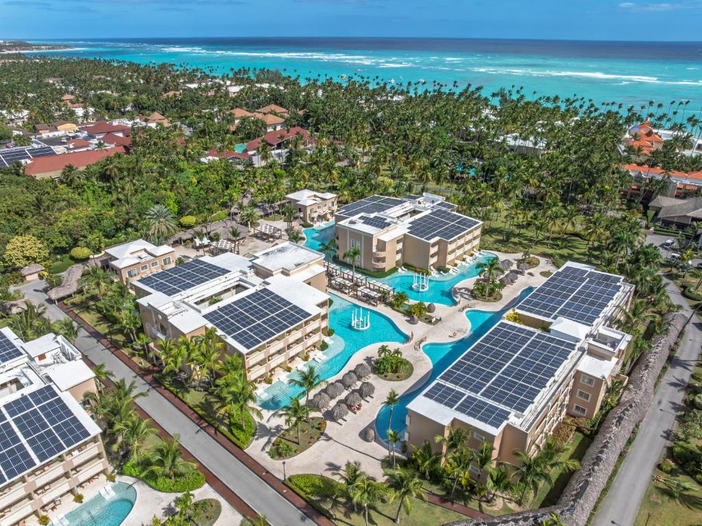 Aerial view of beachfront resort complex with pools, buildings, and ocean backdrop.