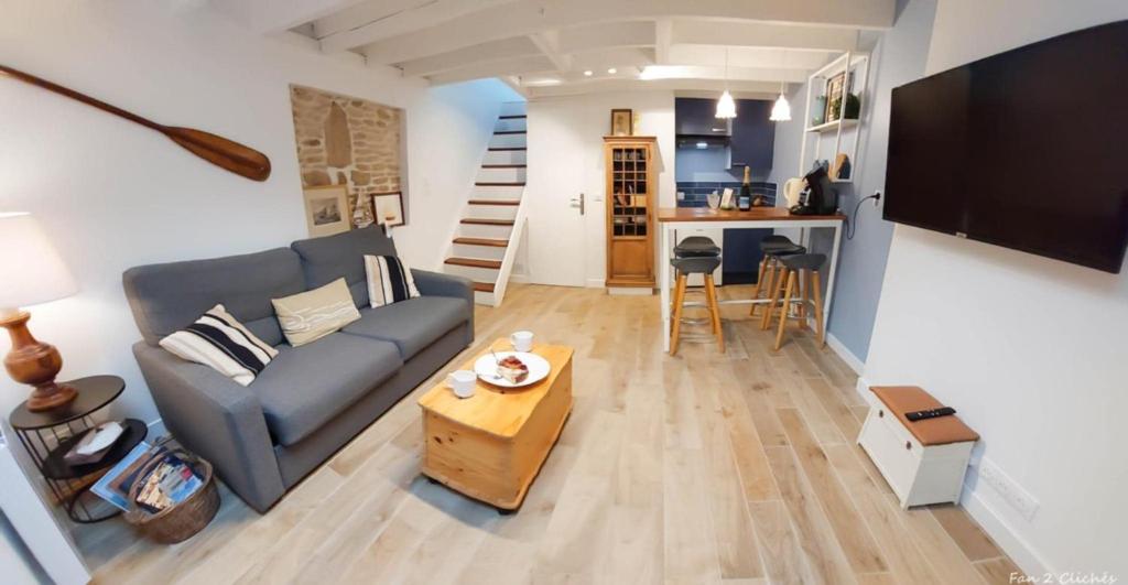 a living room with a couch and a table at Séjour couple ou solo Maisonnette tout confort - calme et proximité commerces, plage, restaurants et axes routiers in Ouistreham