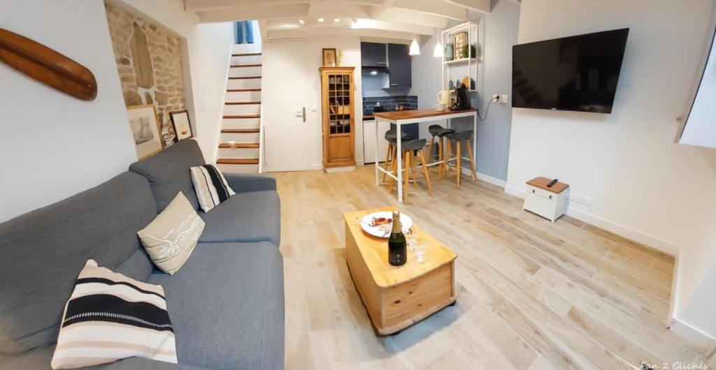 ein Wohnzimmer mit einem blauen Sofa und einem Tisch in der Unterkunft La Coquille Séjour en Duo Confort Maisonnette de bourg à Ouistreham - Situation idéale commerces & plage - Wifi et linge inclus in Ouistreham