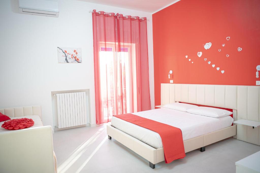 a bedroom with red walls and a bed and a window at Le Cromie di Amelie in Ceglie Messapica