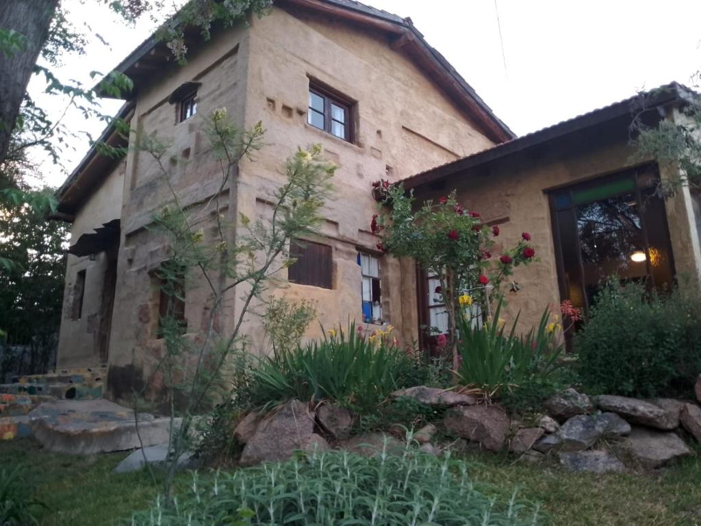 a stone house with a garden in front of it at Casa Amarilla in Mina Clavero