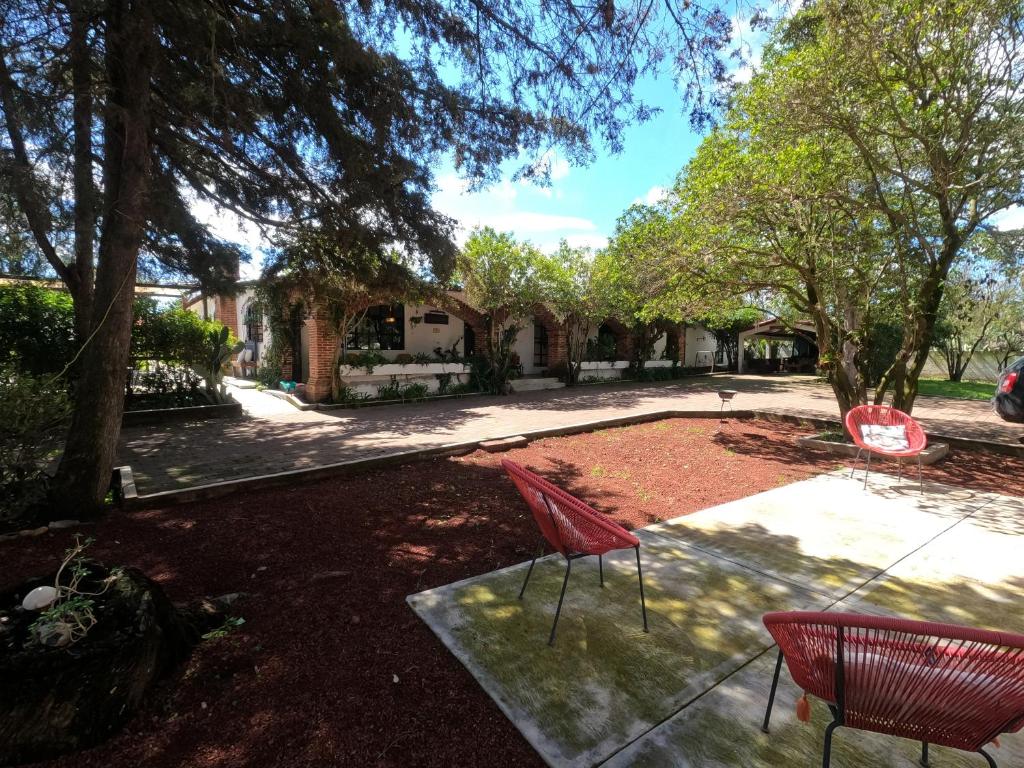 duas cadeiras vermelhas em um quintal com árvores em Finca del Pomar em Acatlán