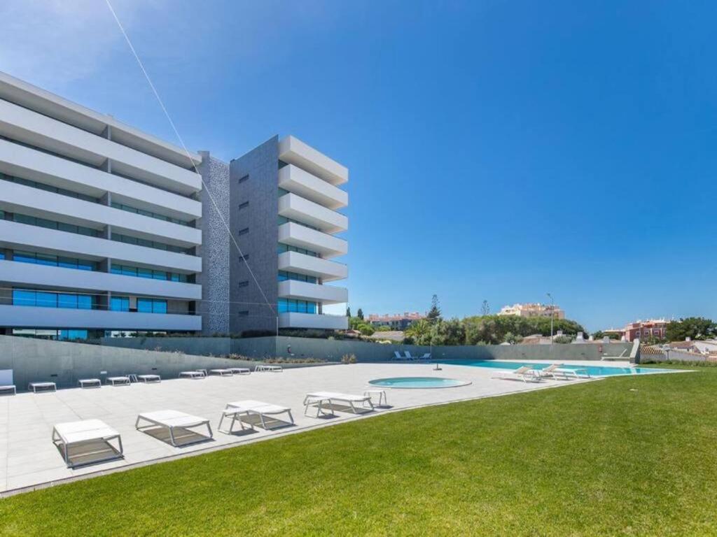 a building with a pool and chairs and a lawn at Sea View Apartment in Santo Amaro