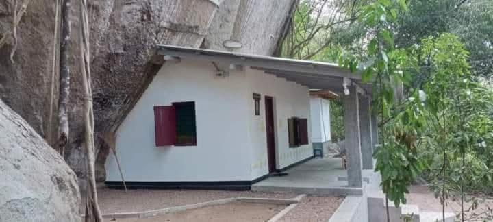 un pequeño edificio blanco con ventanas rojas y verdes en Thalpathwewa Cave Temple, 