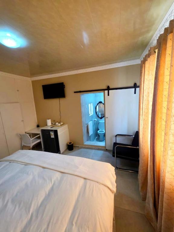 a bedroom with a white bed and a living room at Sweet Home B & B in East London