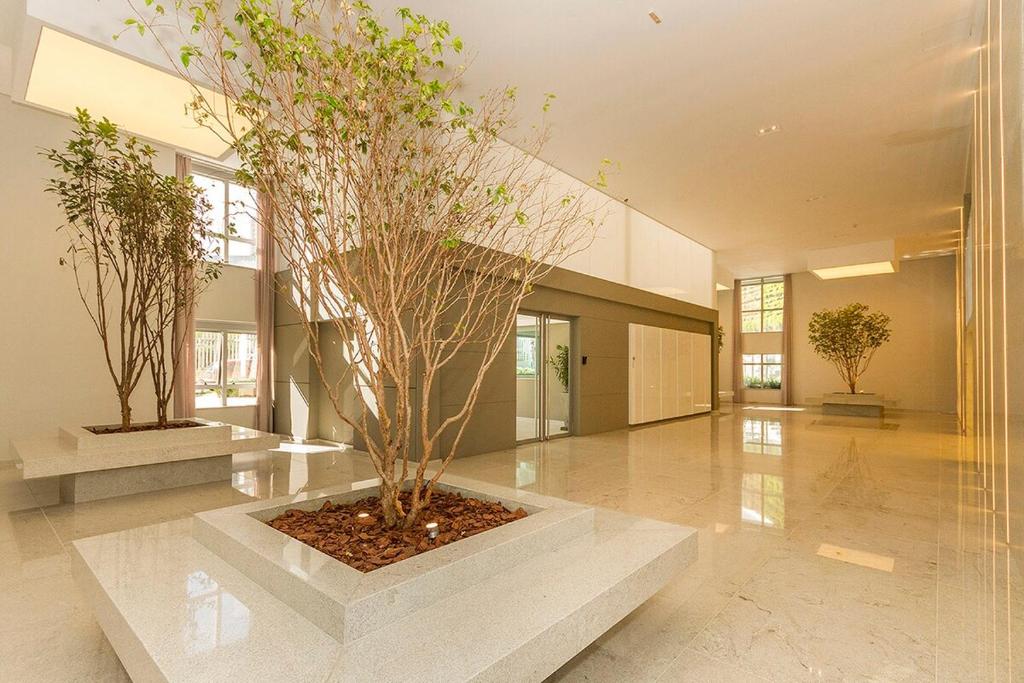 a lobby with two trees in a large building at 413 Trend Residence High Standard in Porto Alegre