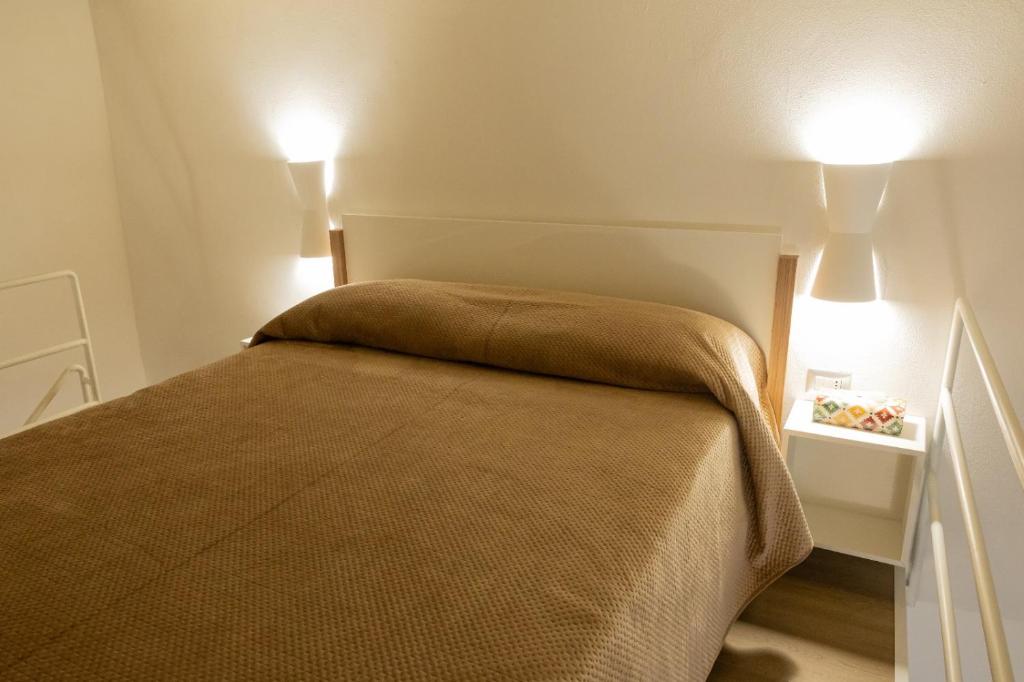 een slaapkamer met een bed met twee lampjes aan de muur bij Le Casarelle in Gaeta