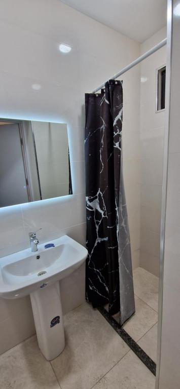a bathroom with a black shower curtain and a sink at Guest house marissi in Surami