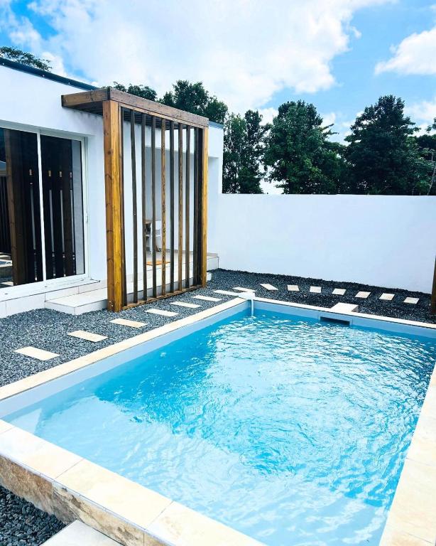 a swimming pool in front of a white wall at Oasis in Petit-Bourg