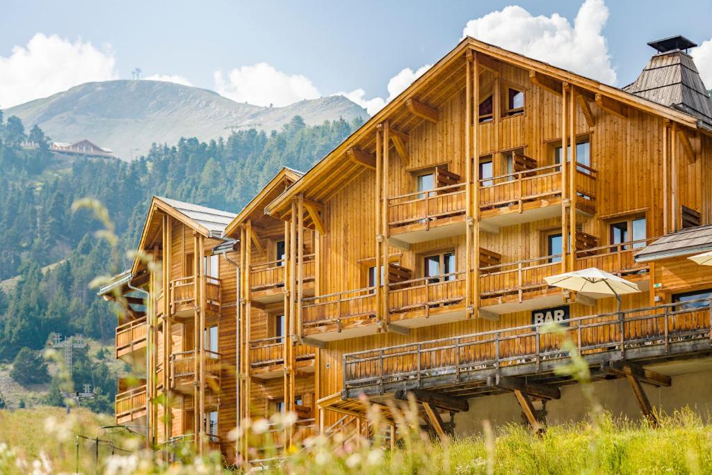 un edificio de madera con una montaña en el fondo en Anova Hotel & Spa en Montgenèvre