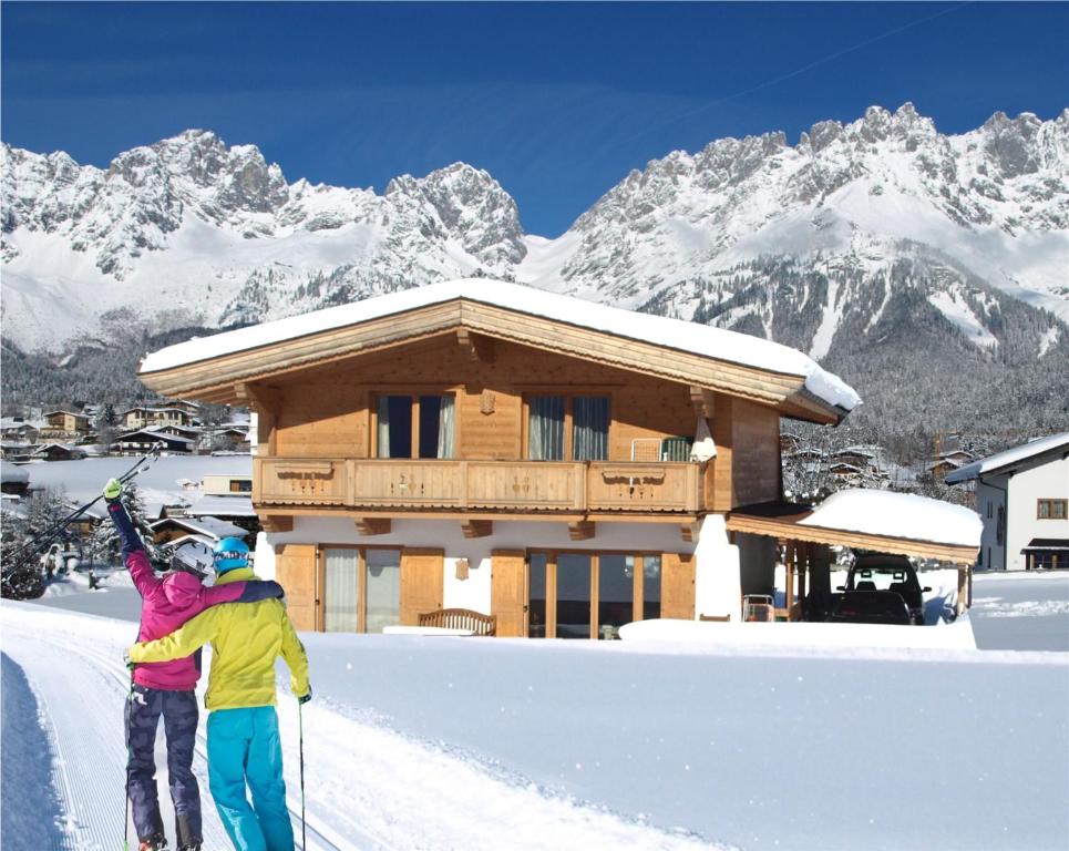two people on skis in the snow in front of a cabin at Chalet Der Tyroler Adler im Zentrum vom Wilden Kaiser in Going