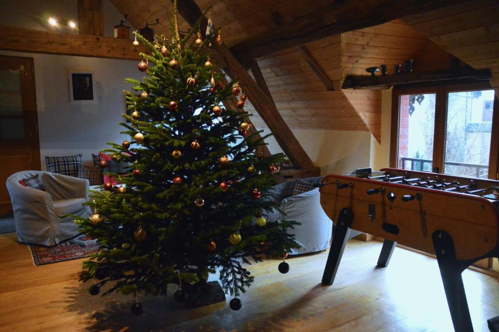 a christmas tree in a living room with a table at Cottage Mackinley, séjour convivial, jeux, grand sapin de Noël, et contes,15 pers, Centre Historique, gare TER in Aubigny-sur-Nère