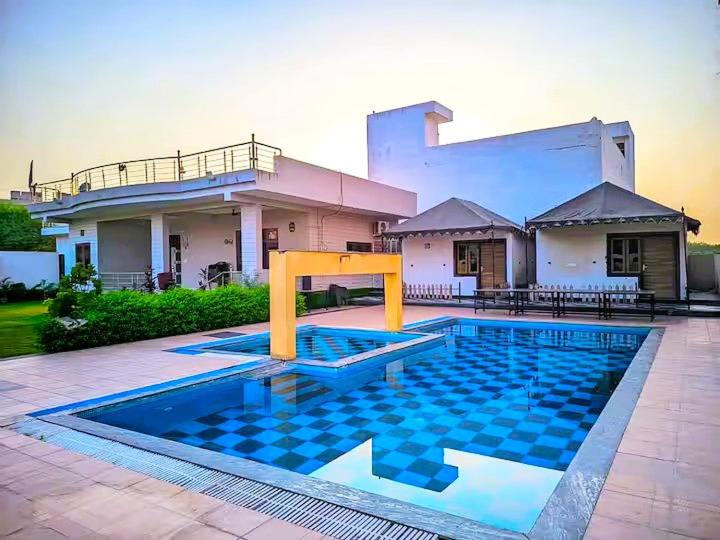 a house with a swimming pool in front of a house at The Starlight Farmstay- Poolside Tent Stay in Jaipur in Jāmb