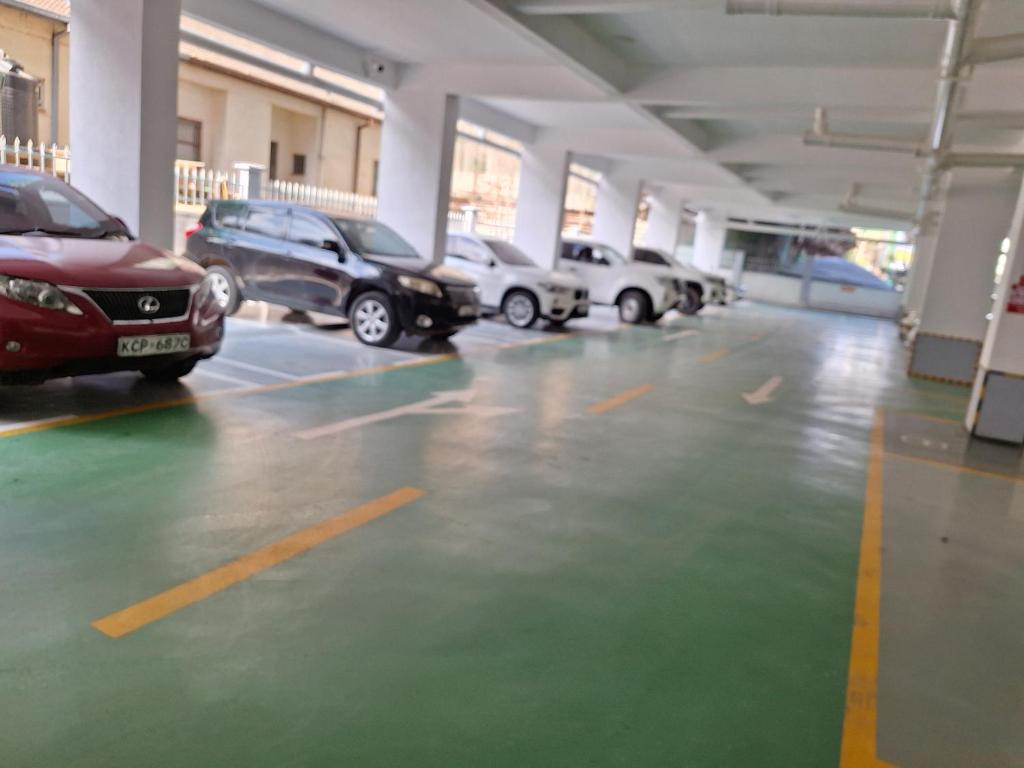 a parking lot with several cars parked in it at Golden Mango Heights - Urban Family Suite - One Bedroom Apartment - Restaurant, Workspace, City Views, Fast WiFi, Sauna, Fitness Facilities, Secure Parking And Kids Play Area in Nairobi