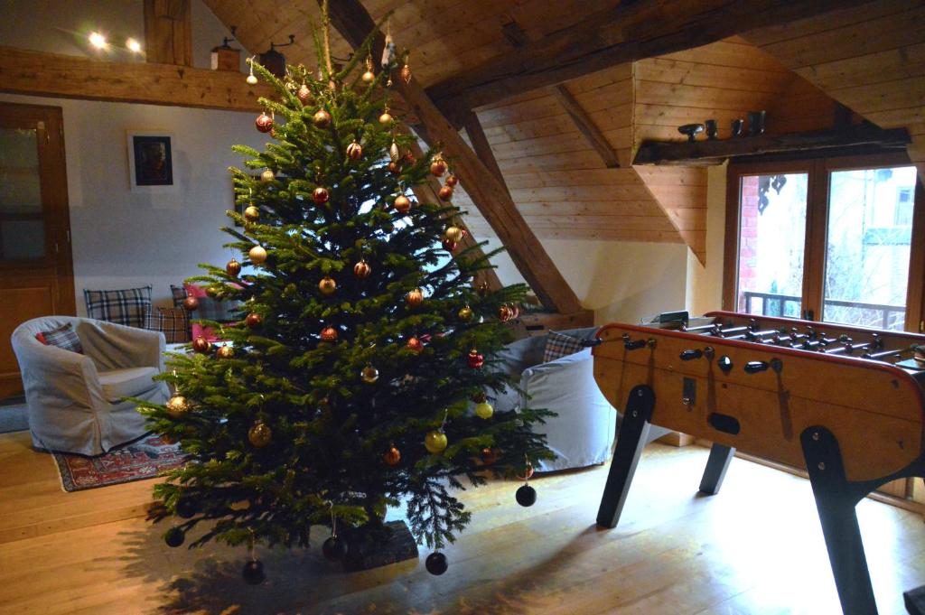 a christmas tree in a living room with a table at Cottage Mackinley, séjour convivial, jeux, grand sapin de Noël, et contes,15 pers, Centre Historique, gare TER in Aubigny-sur-Nère