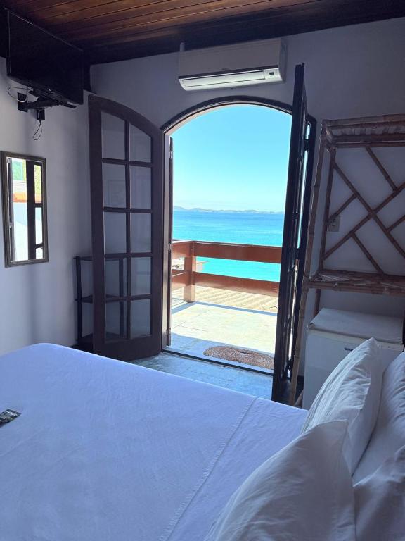 a bedroom with a bed and a view of the ocean at Pousada Vó Nina in Arraial do Cabo